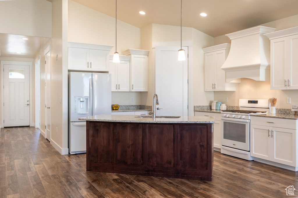 Kitchen with custom exhaust hood, dark hardwood / wood-style flooring, white appliances, white cabinetry, and pendant lighting