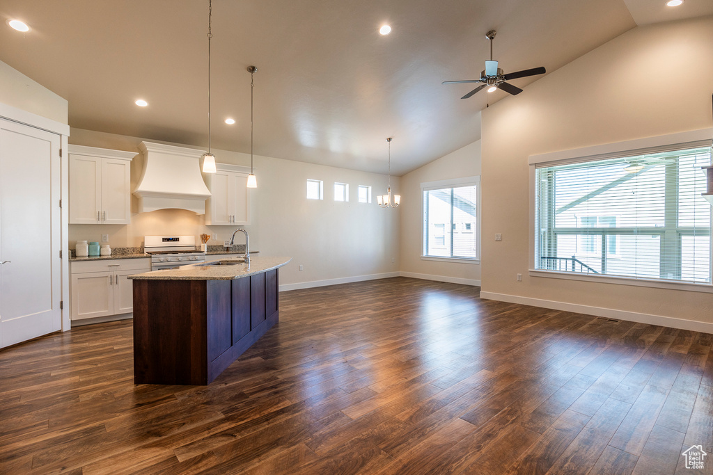 Kitchen with premium range hood, stainless steel range oven, dark wood-type flooring, decorative light fixtures, and light stone countertops