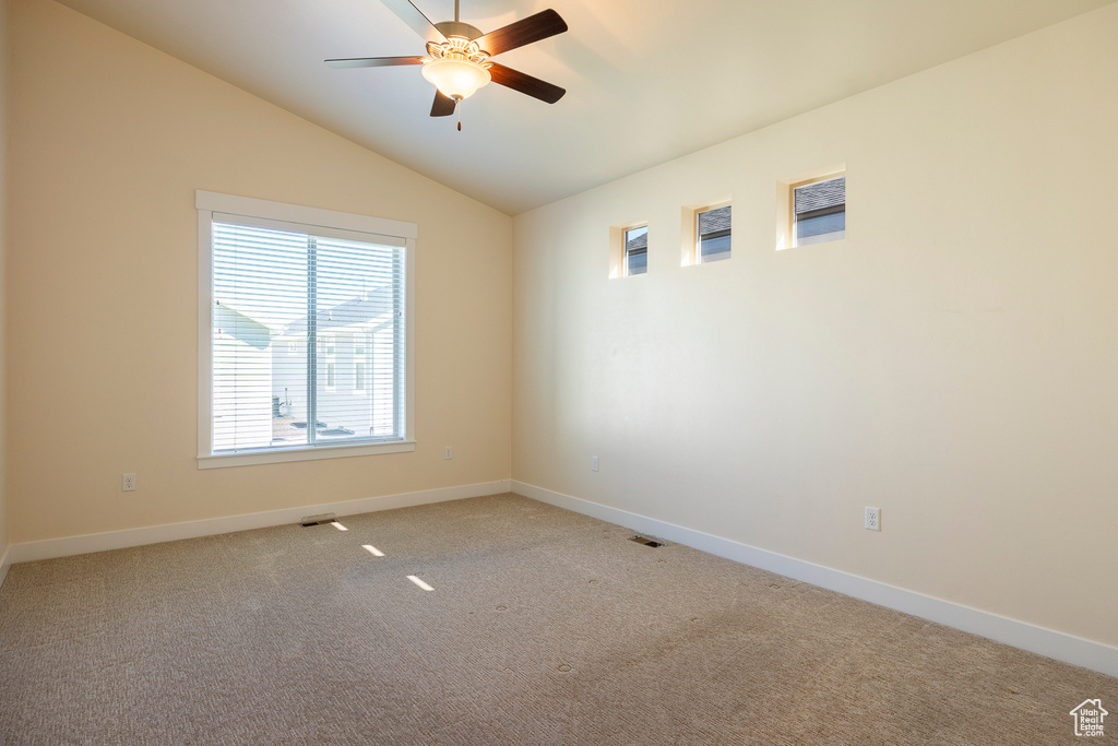 Carpeted empty room with lofted ceiling and ceiling fan