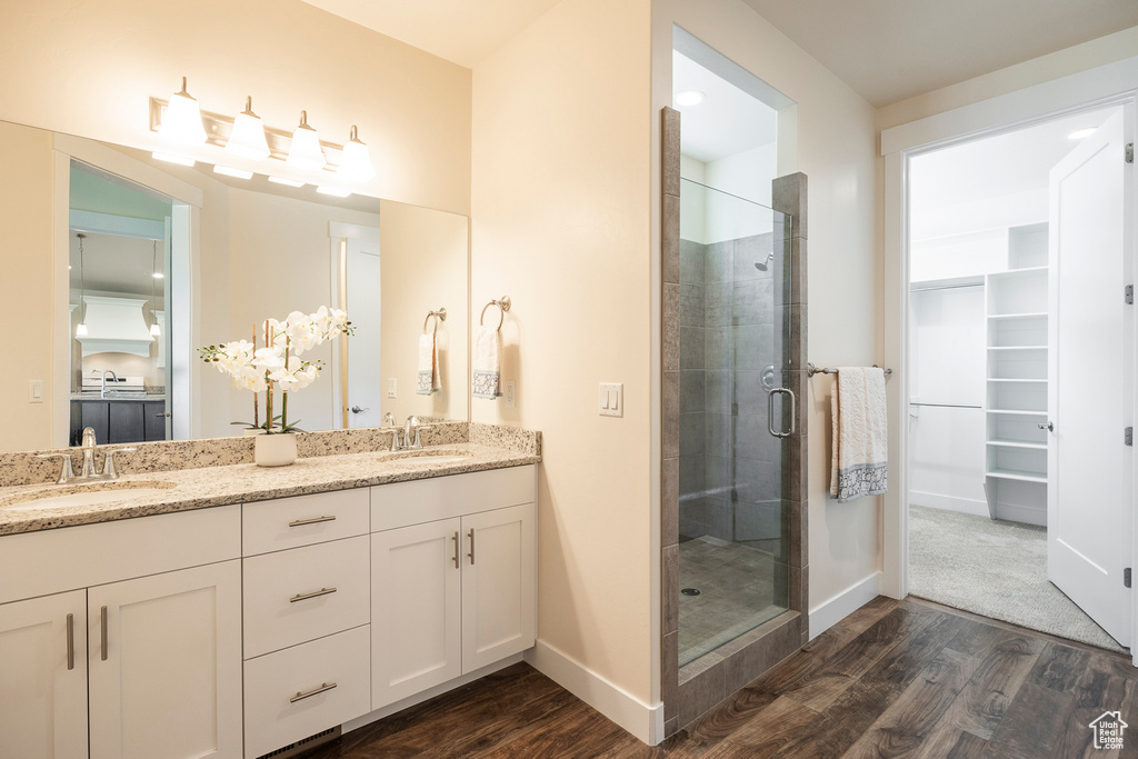 Bathroom featuring a shower with door, double sink vanity, and hardwood / wood-style floors