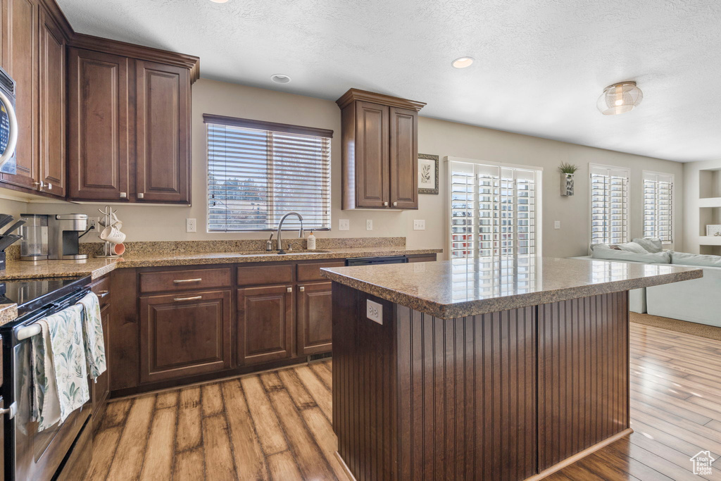 Kitchen featuring sink, light hardwood / wood-style flooring, dark brown cabinetry, and stove