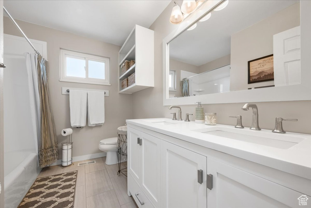 Full bathroom with dual vanity, toilet, shower / bath combination with curtain, and tile flooring
