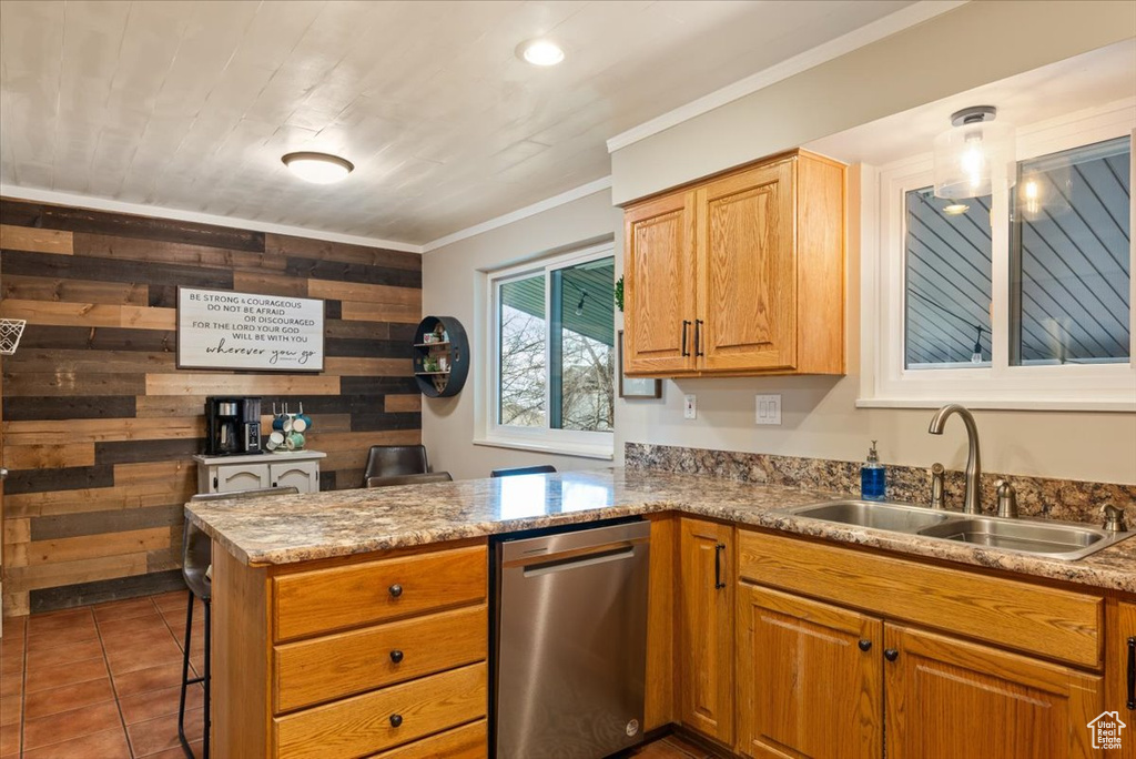 Kitchen with dark tile flooring, sink, wooden walls, dishwasher, and light stone counters