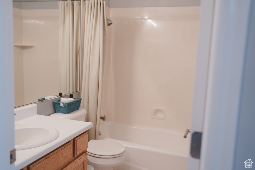 Full bathroom featuring shower / bathtub combination with curtain, toilet, and vanity