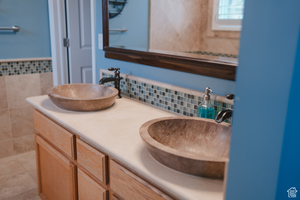 Bathroom with dual bowl vanity, tile flooring, and tasteful backsplash