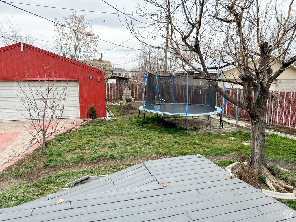 View of yard with a garage, a deck, and a trampoline