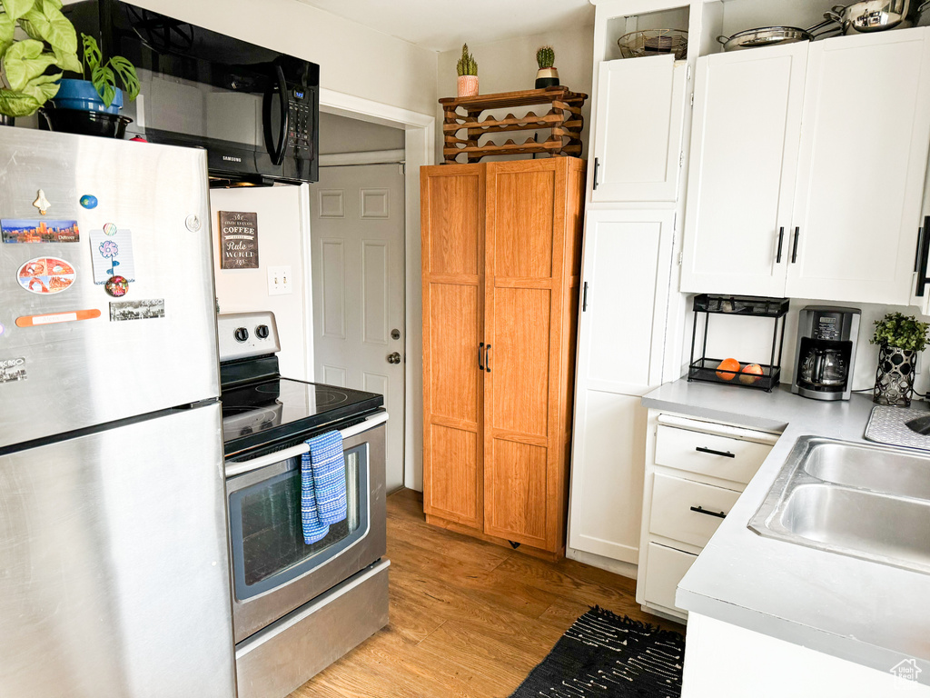 Kitchen with white cabinets, white refrigerator, light hardwood / wood-style flooring, and electric range