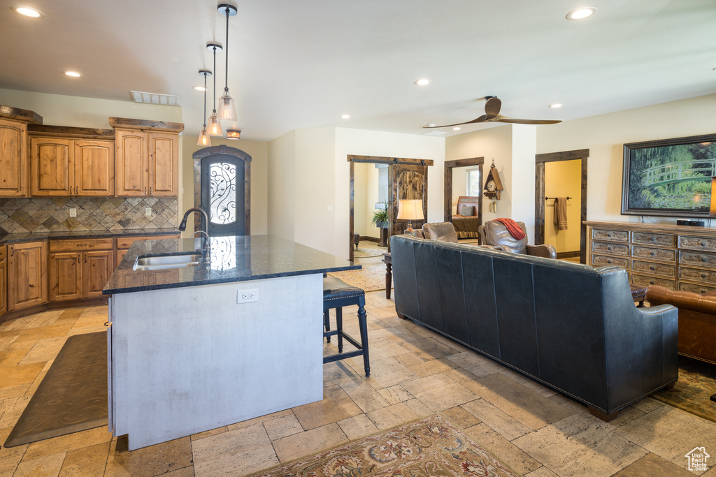 Kitchen featuring a kitchen island with sink, a kitchen breakfast bar, sink, light tile floors, and ceiling fan