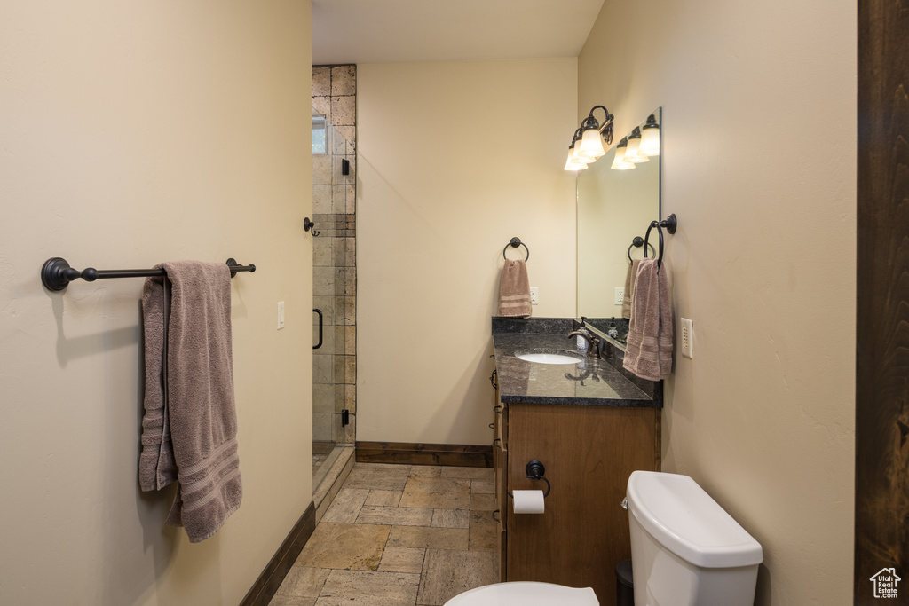 Bathroom featuring vanity with extensive cabinet space, tile floors, toilet, and walk in shower