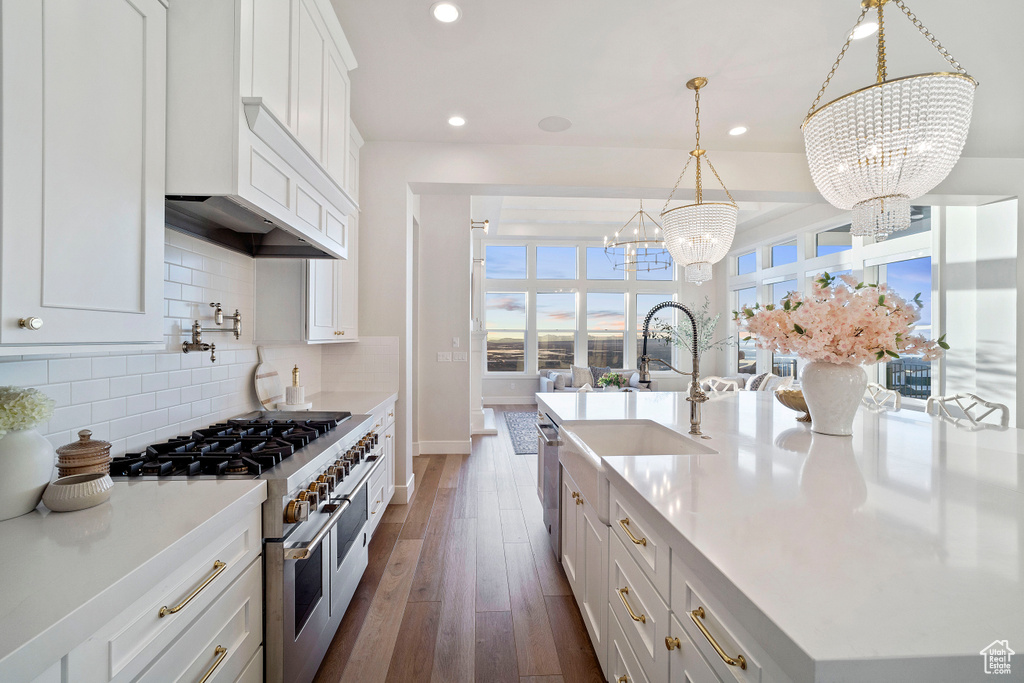 Kitchen with tasteful backsplash, appliances with stainless steel finishes, a chandelier, white cabinets, and pendant lighting
