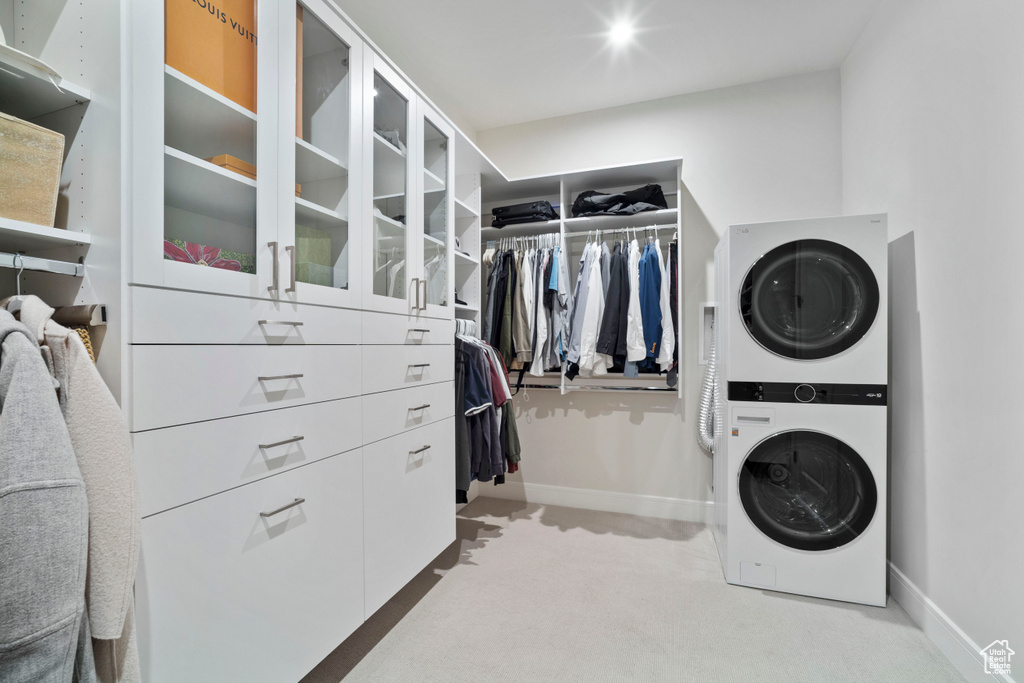 Spacious closet featuring stacked washer / drying machine and light colored carpet