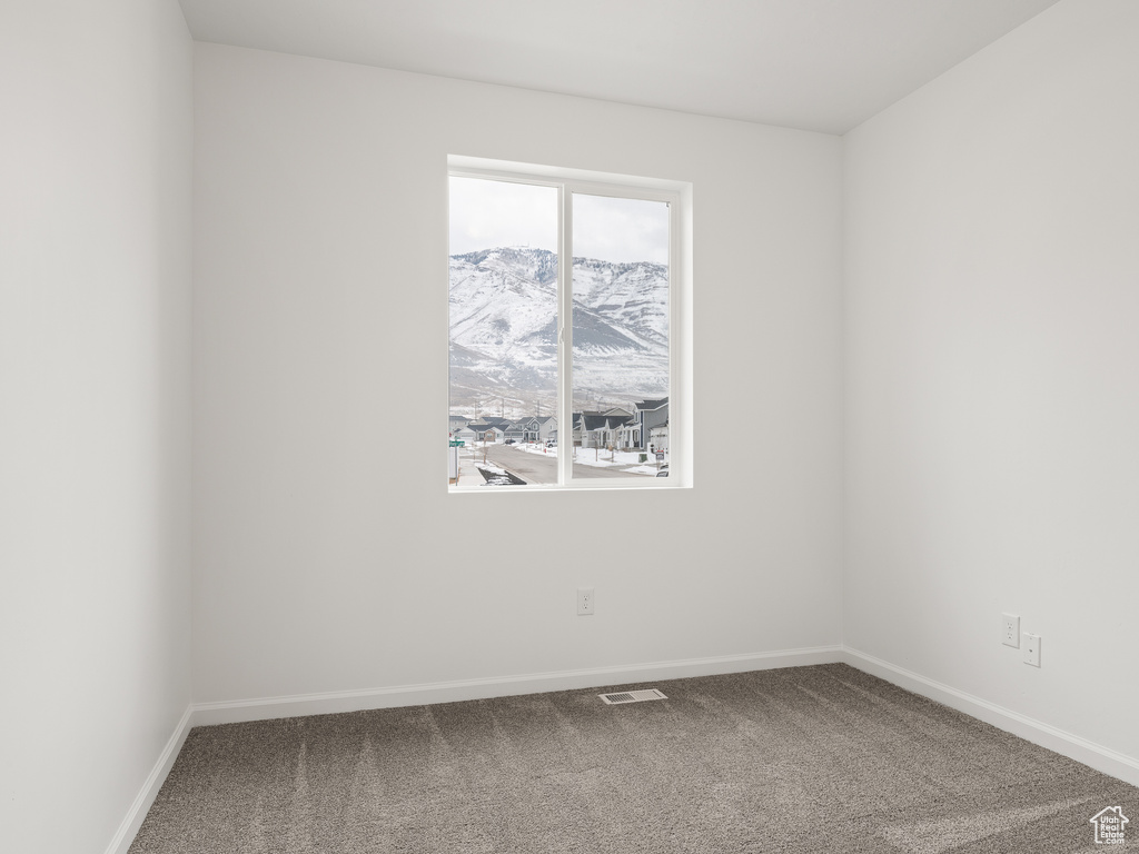 Empty room with a mountain view, carpet, and a healthy amount of sunlight