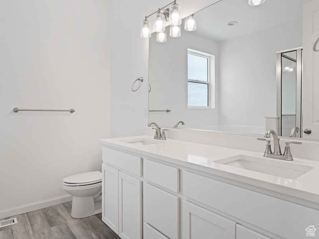 Bathroom featuring dual bowl vanity, hardwood / wood-style floors, and toilet