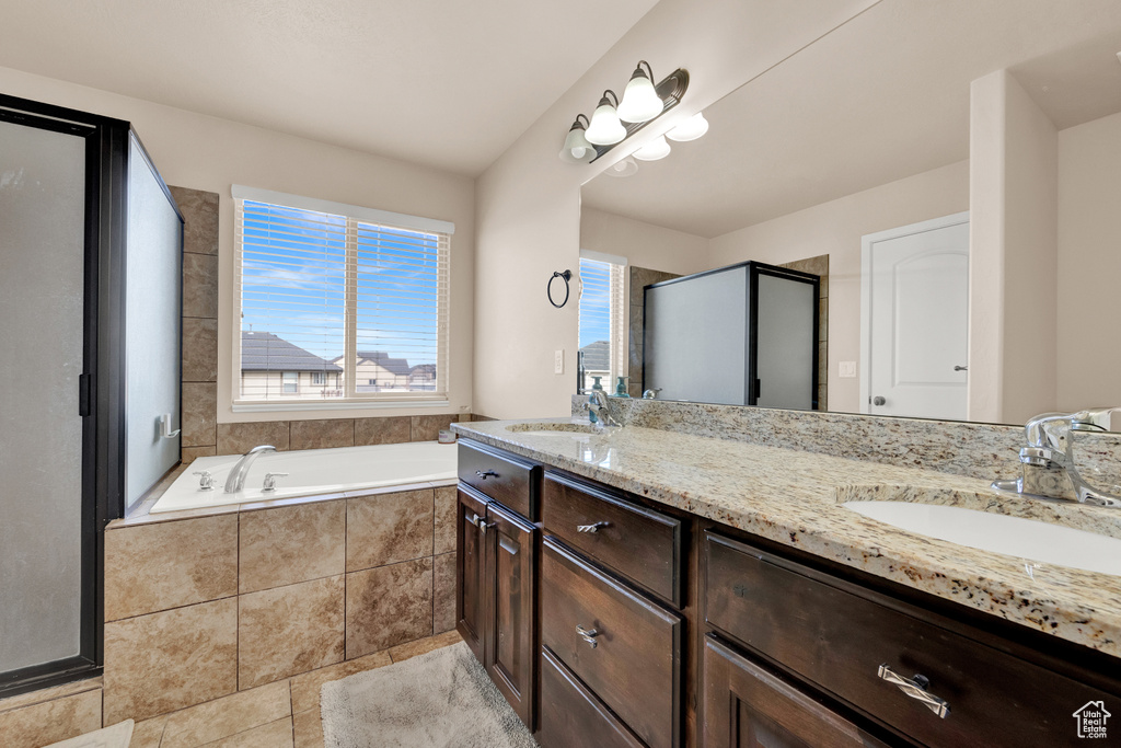 Bathroom with independent shower and bath, double sink vanity, and tile floors