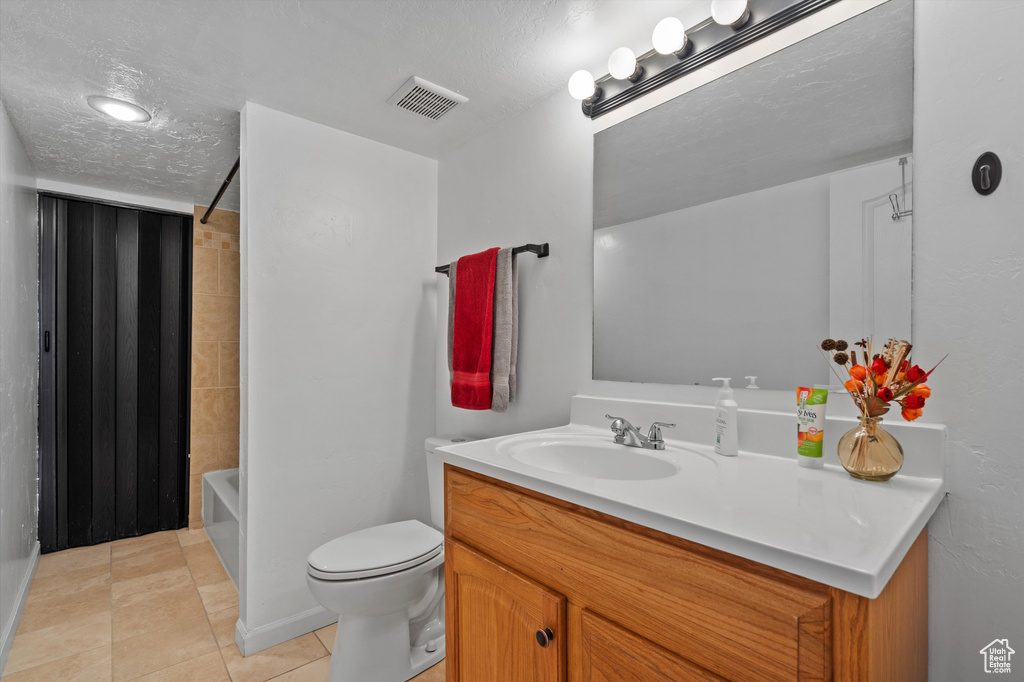 Full bathroom with vanity, a textured ceiling,  shower combination, toilet, and tile floors
