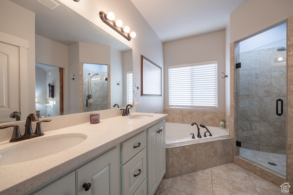 Bathroom featuring double sink vanity, shower with separate bathtub, and tile floors