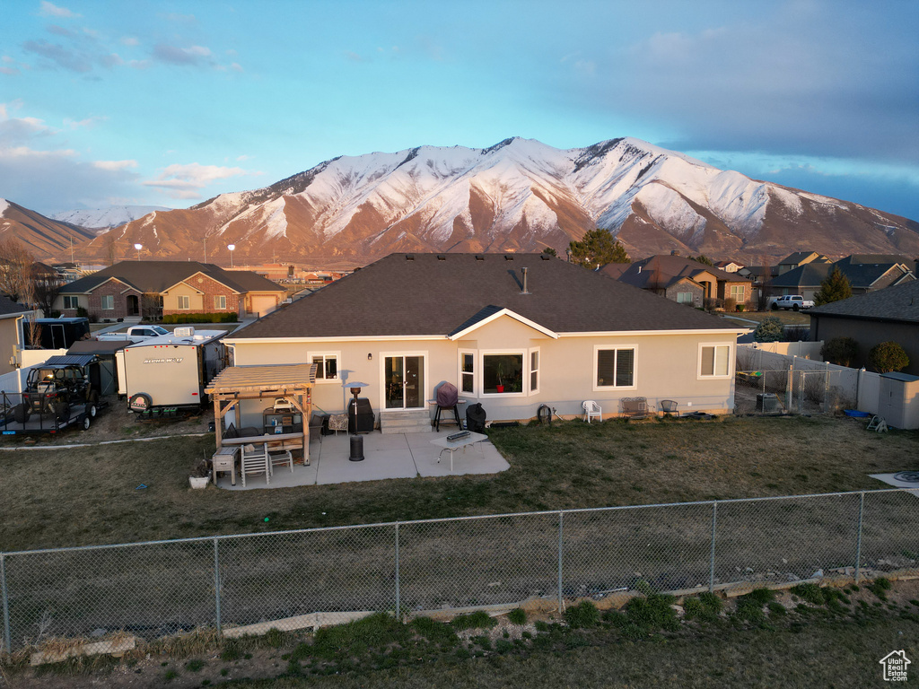 Rear view of property with a patio, a yard, and a mountain view