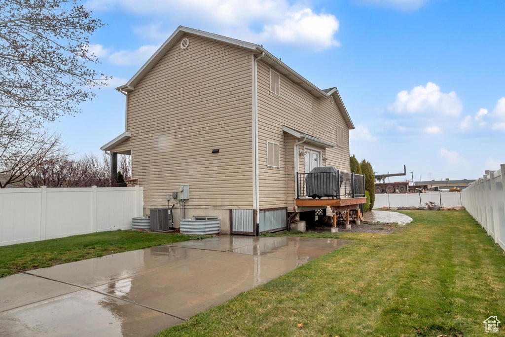 Back of house featuring a patio, a yard, central air condition unit, and a wooden deck