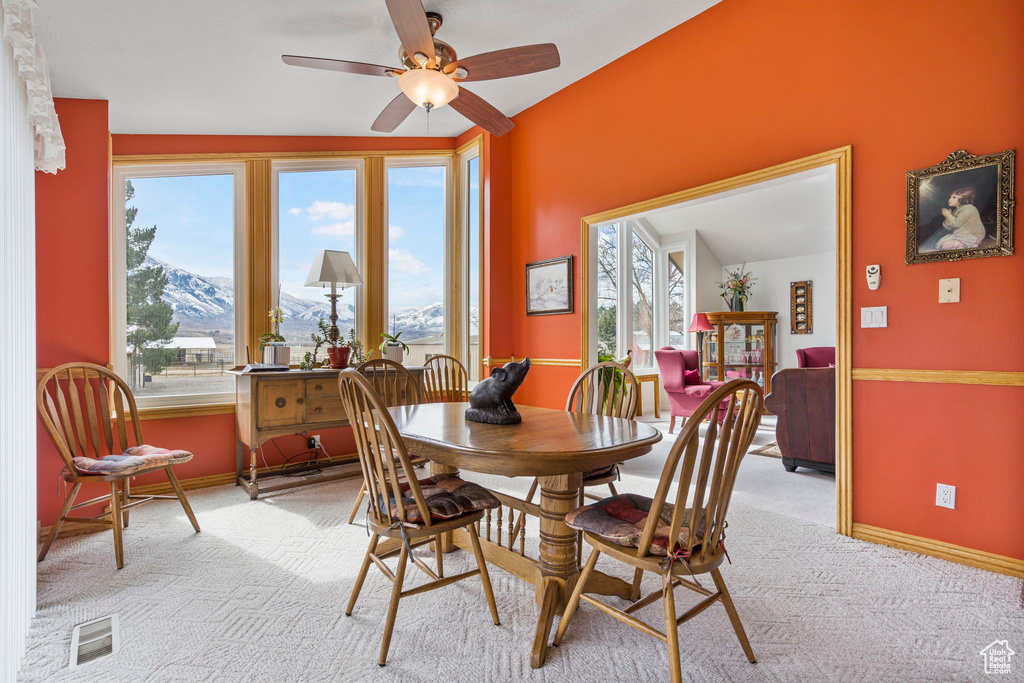 Dining area featuring a mountain view, light carpet, and a healthy amount of sunlight