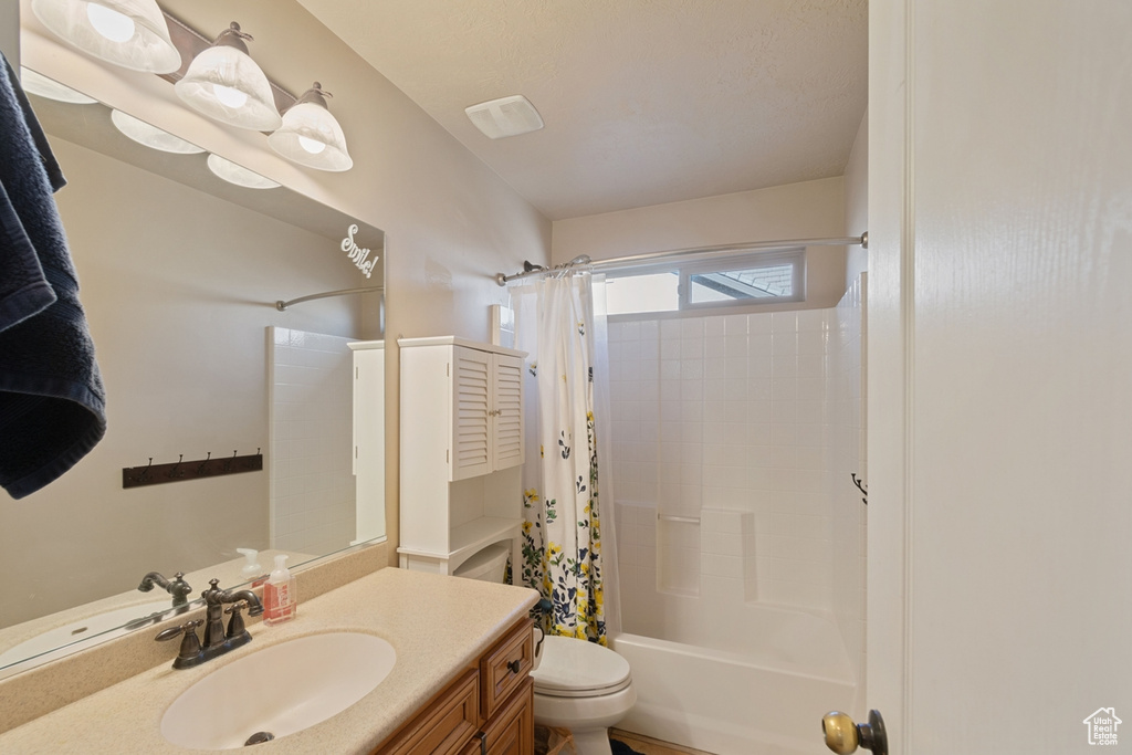 Full bathroom featuring oversized vanity, shower / bath combination with curtain, and toilet