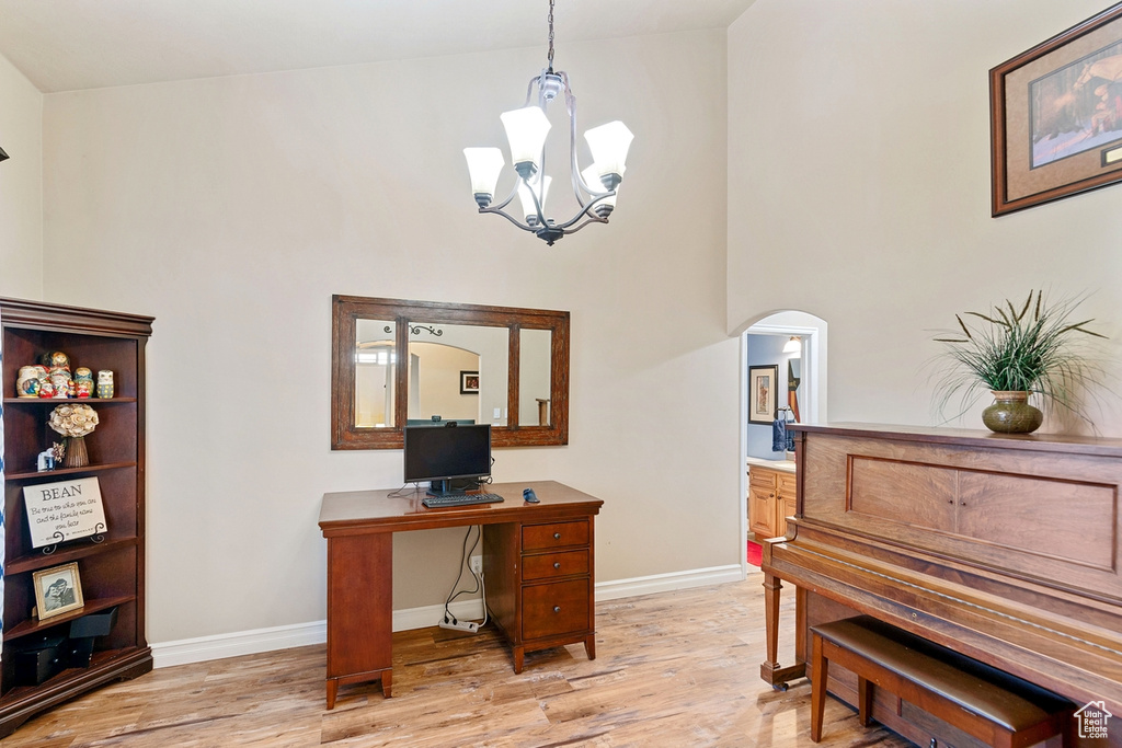 Office area featuring an inviting chandelier, a high ceiling, and light hardwood / wood-style floors