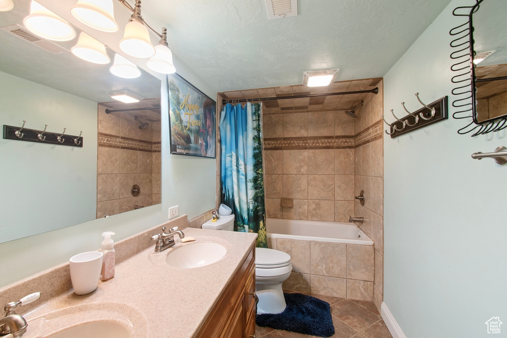 Full bathroom featuring toilet, vanity with extensive cabinet space, shower / tub combo, and tile flooring