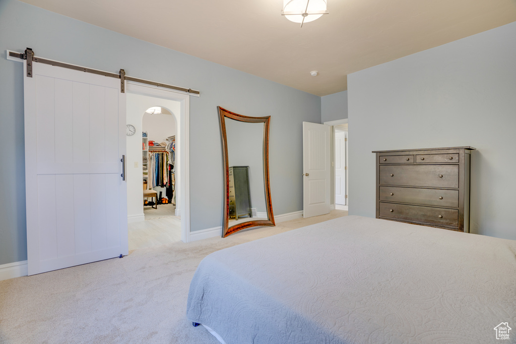 Carpeted bedroom featuring a spacious closet, a barn door, and a closet