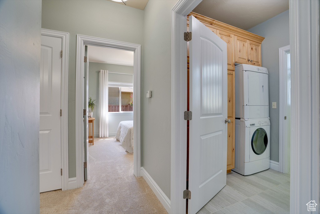 Laundry room with stacked washer / drying machine and light carpet