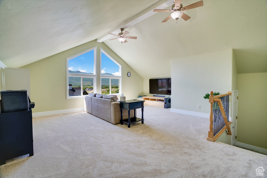 Living room featuring light colored carpet, vaulted ceiling with beams, and ceiling fan