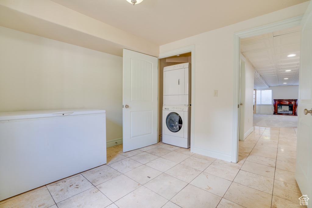 Laundry area featuring light tile flooring and stacked washer and clothes dryer