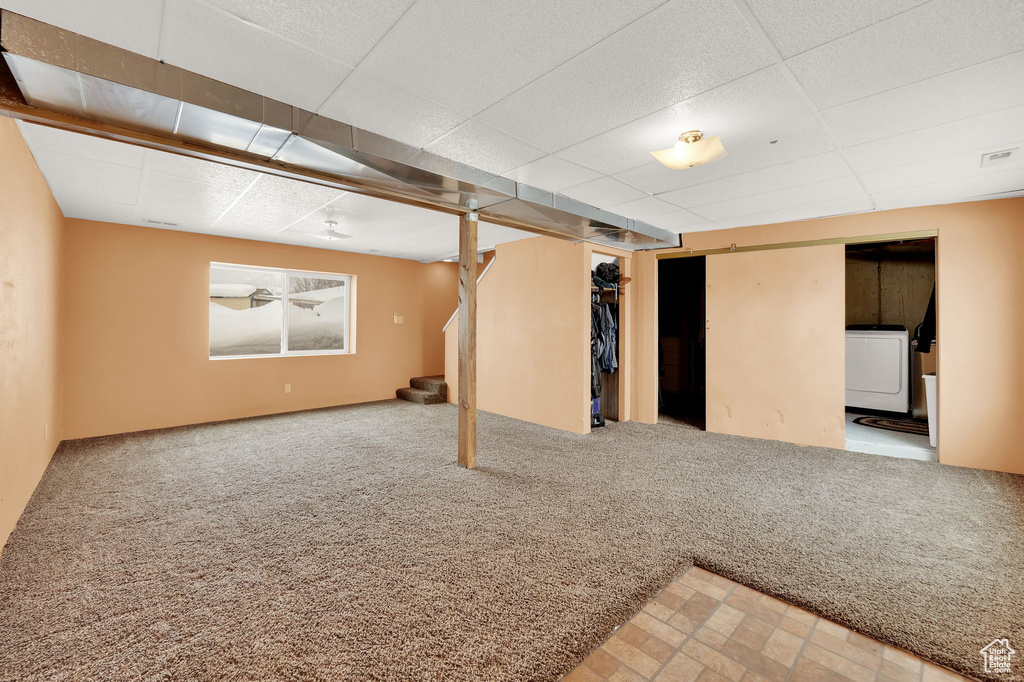 Basement featuring washer / dryer, light carpet, and a paneled ceiling