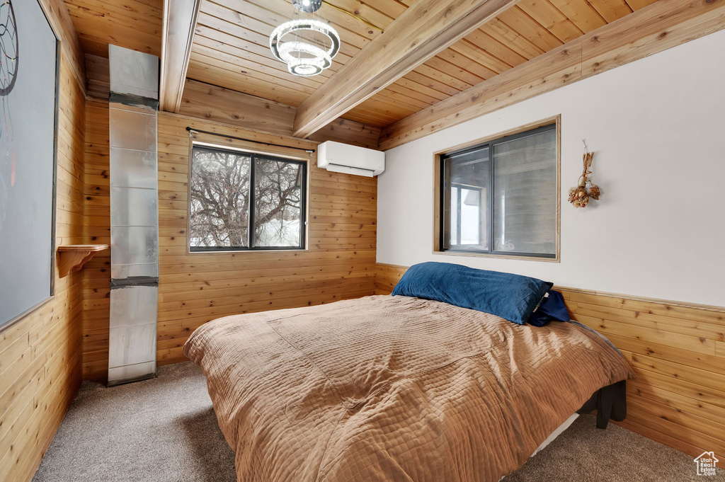 Carpeted bedroom with wooden walls, wooden ceiling, an AC wall unit, and beamed ceiling