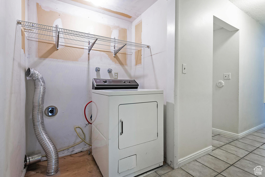Clothes washing area featuring washer / dryer and light tile floors