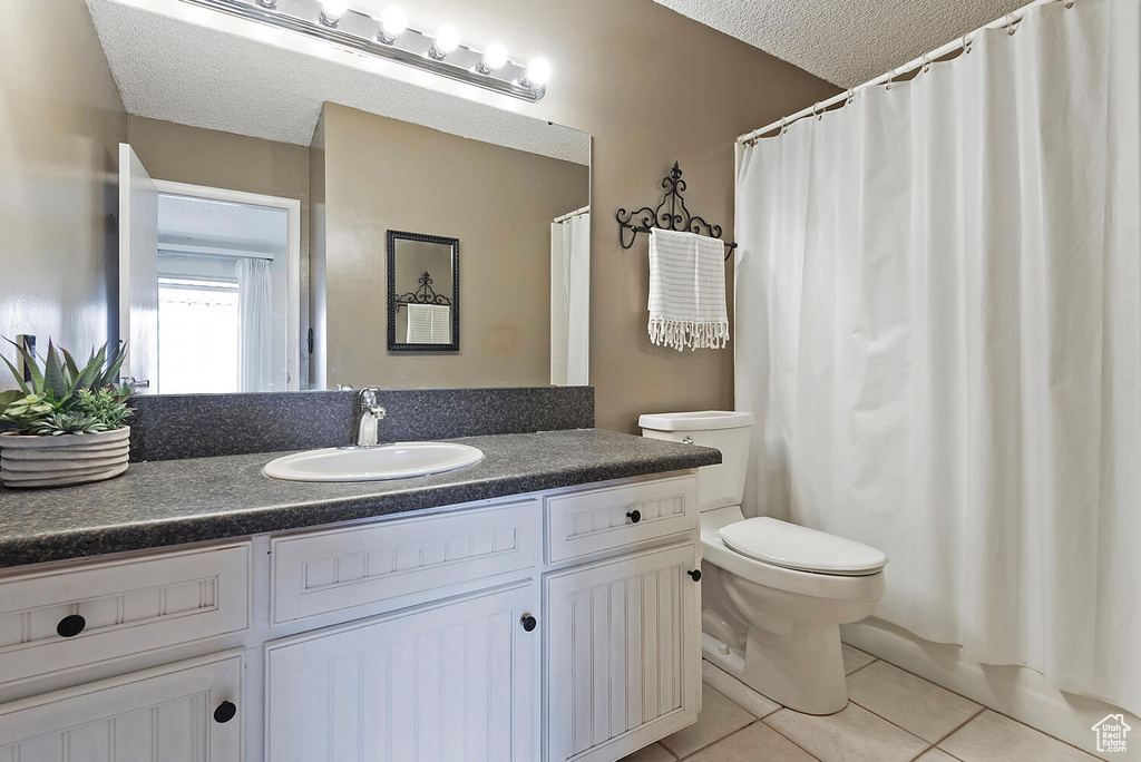 Bathroom featuring vanity, toilet, tile flooring, and a textured ceiling