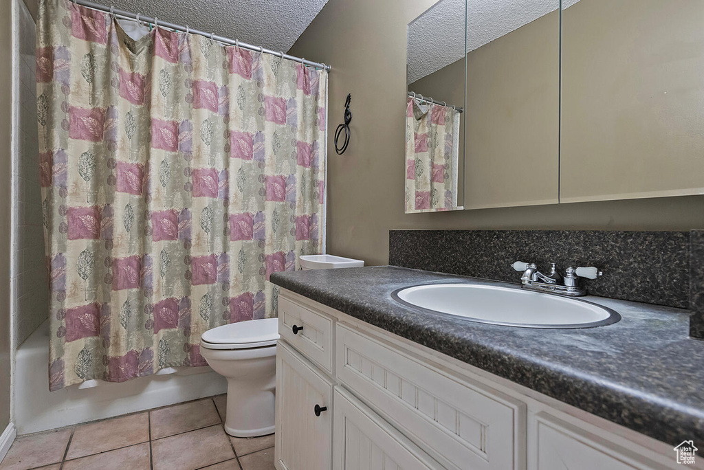Full bathroom featuring tile floors, a textured ceiling, toilet, shower / bath combination with curtain, and vanity