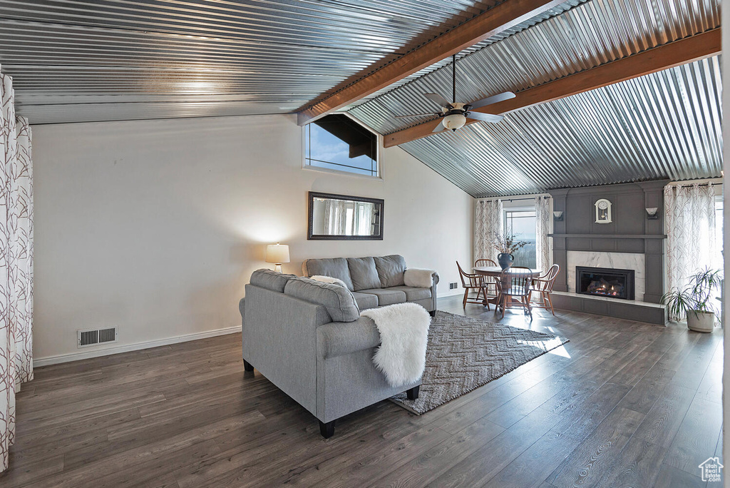 Living room featuring lofted ceiling with beams, ceiling fan, a tile fireplace, and dark hardwood / wood-style floors