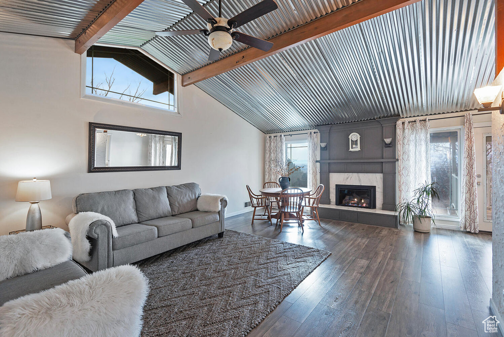 Living room featuring a fireplace, dark hardwood / wood-style flooring, vaulted ceiling with beams, and ceiling fan