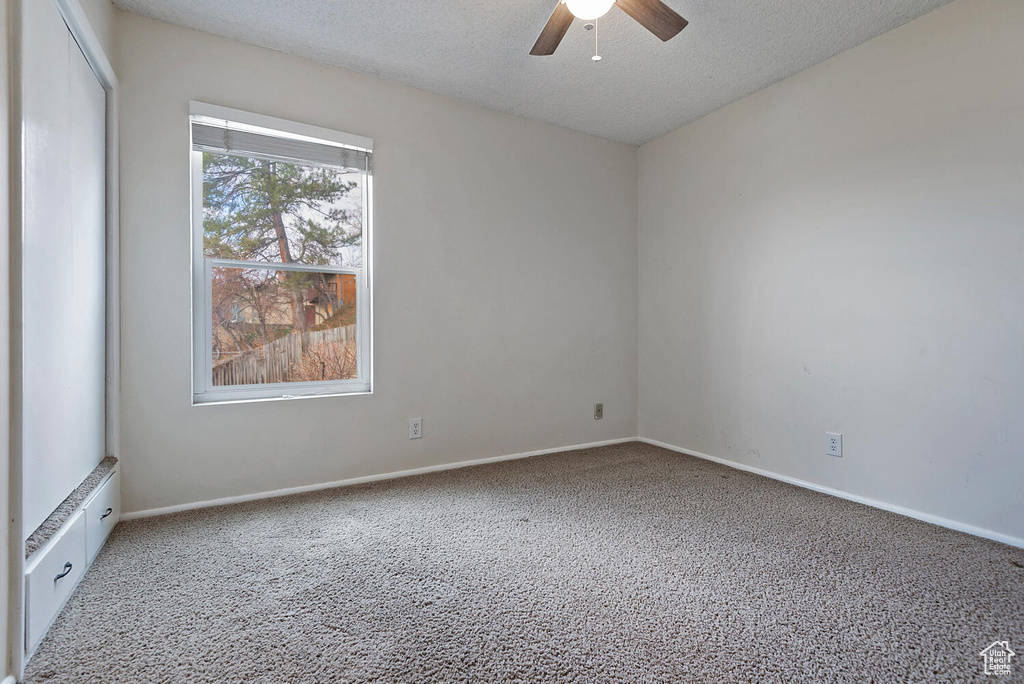 Carpeted spare room with a textured ceiling and ceiling fan