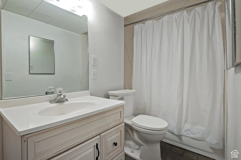 Full bathroom with tile flooring, oversized vanity, toilet, and shower / tub combo with curtain