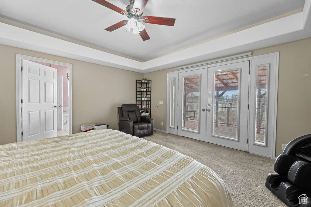 Carpeted bedroom with access to outside, a tray ceiling, french doors, and ceiling fan