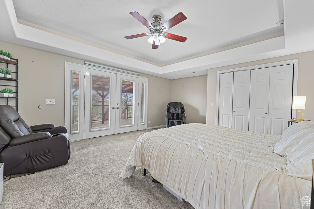 Bedroom featuring a raised ceiling, light colored carpet, french doors, and ceiling fan
