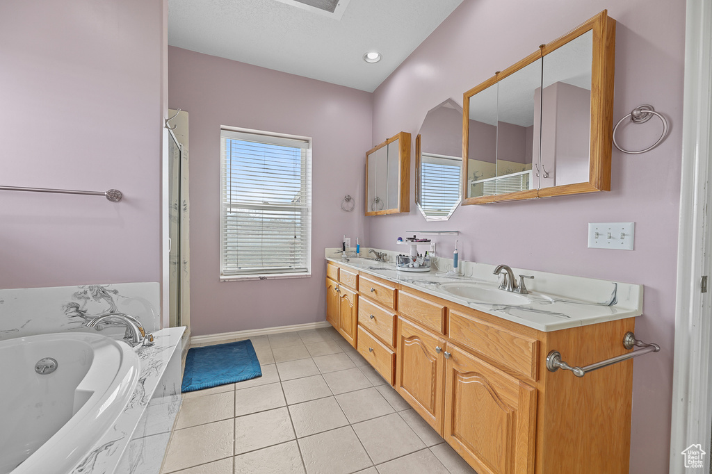 Bathroom with double vanity, shower with separate bathtub, and tile flooring