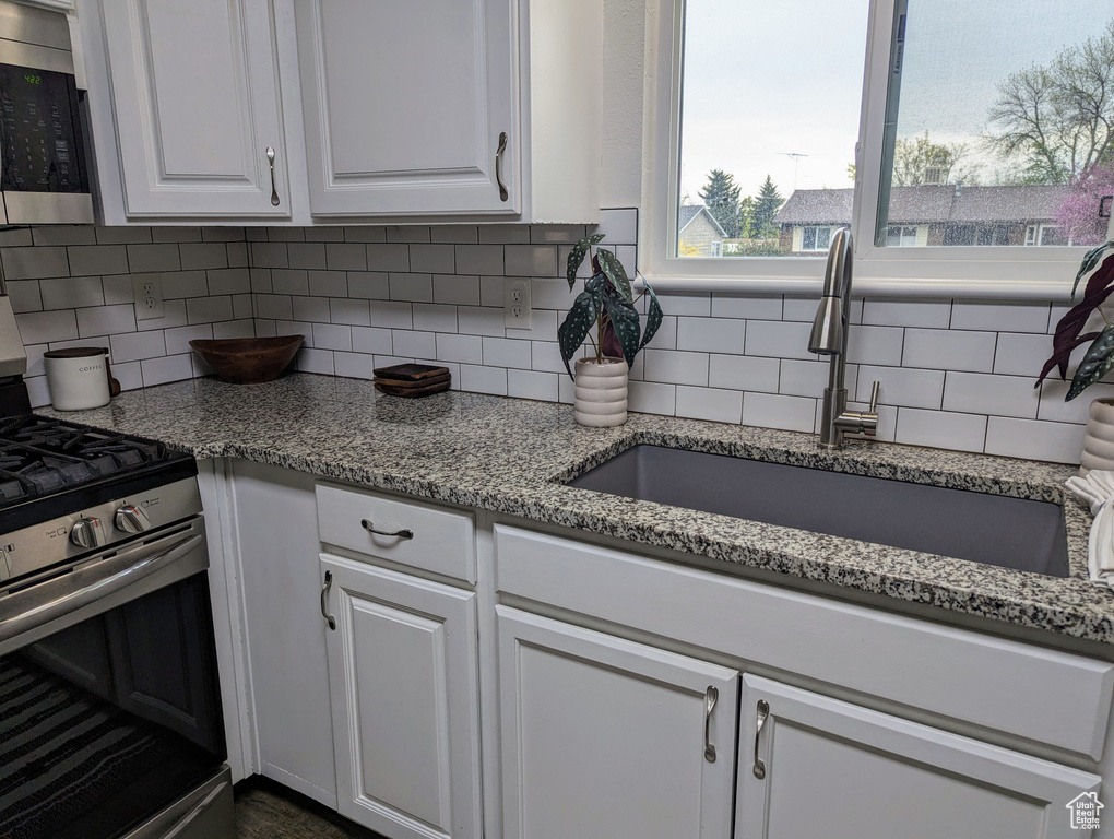 Kitchen featuring white cabinets, backsplash, and appliances with stainless steel finishes