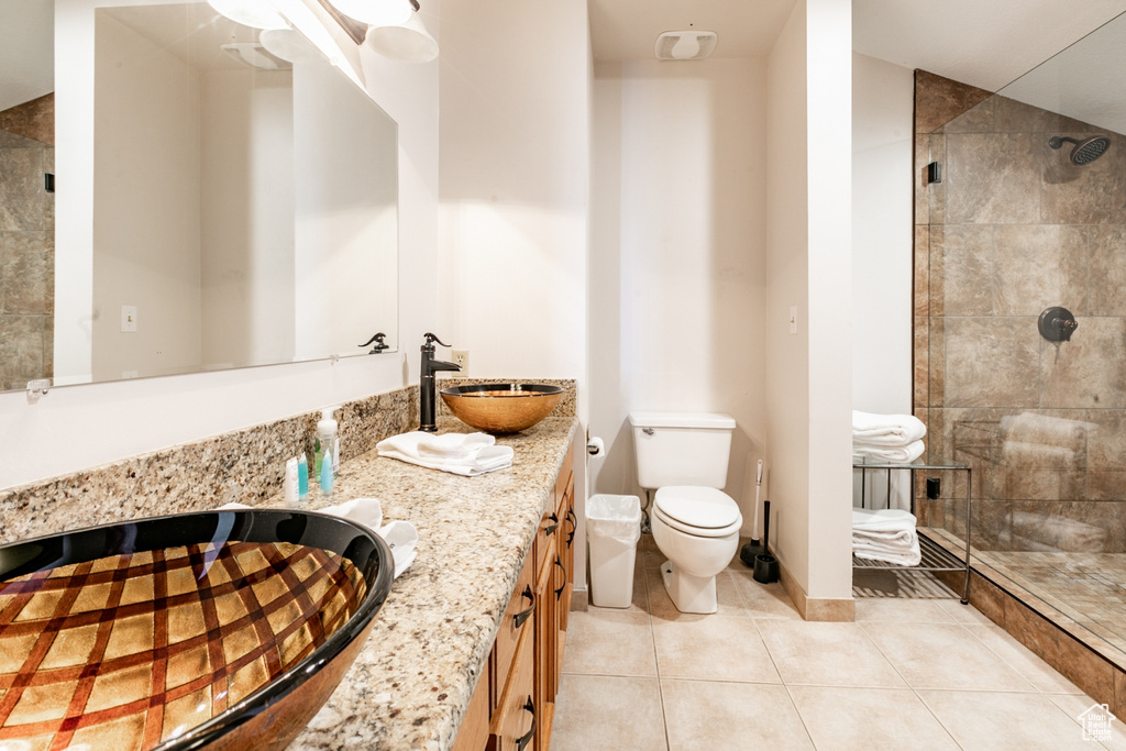 Bathroom featuring toilet, large vanity, walk in shower, and tile flooring