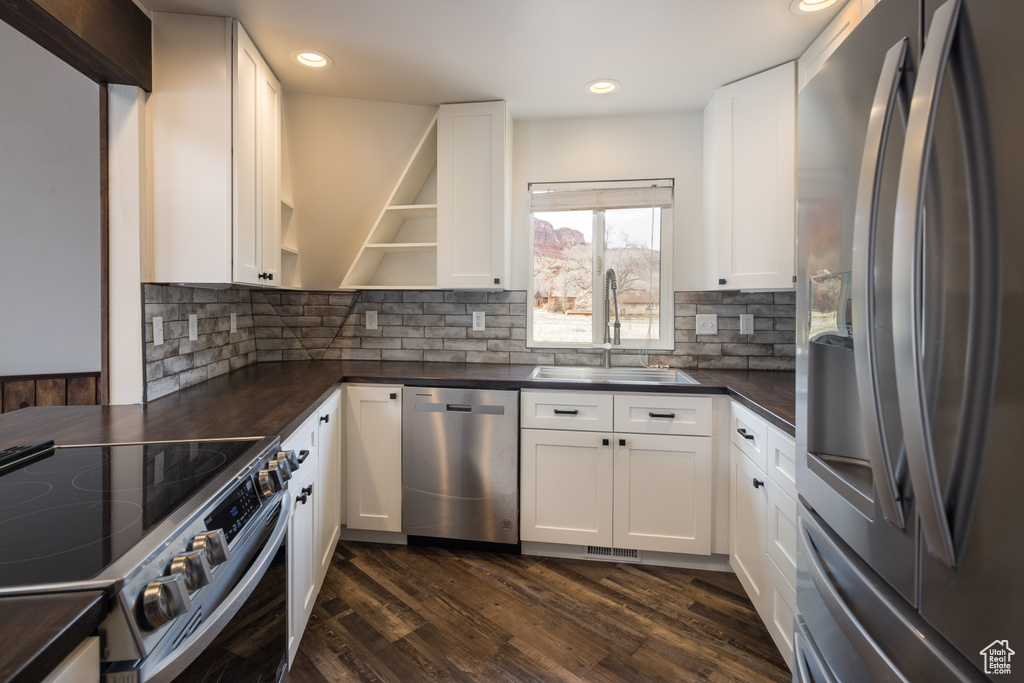 Kitchen featuring appliances with stainless steel finishes, dark hardwood / wood-style flooring, sink, and white cabinets