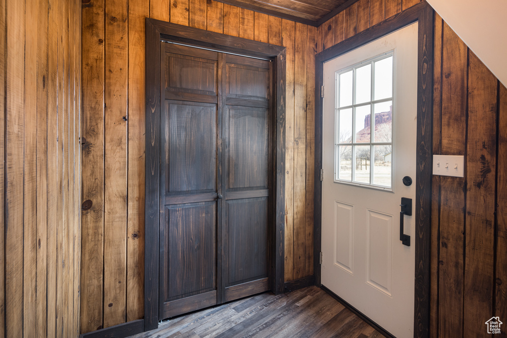 Doorway to outside with dark hardwood / wood-style flooring and wood walls