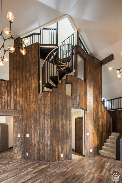 Stairway with a notable chandelier, wooden walls, and dark hardwood / wood-style floors