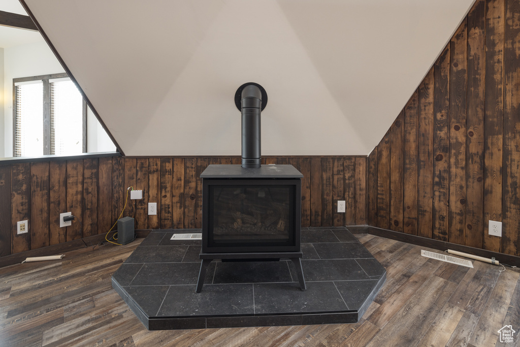 Details featuring a wood stove, wooden walls, and dark hardwood / wood-style floors
