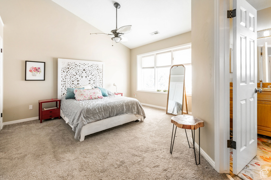 Carpeted bedroom with vaulted ceiling, connected bathroom, and ceiling fan
