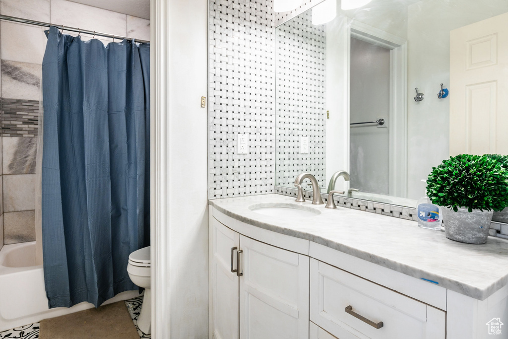 Full bathroom featuring vanity with extensive cabinet space, tile floors, toilet, and shower / tub combo with curtain